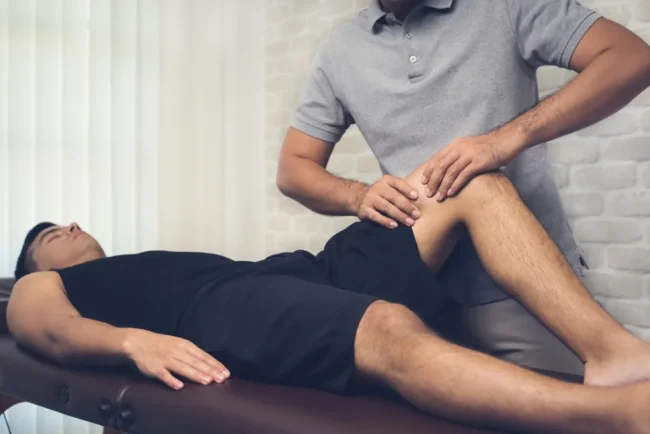 Therapist-treating-injured-leg-of-athlete-male-patient Therapist-treating-injured-leg-of-athlete-male-patient